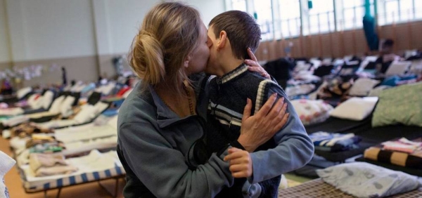 A refugee from Ukraine hugs her son in a reception centre set up in the sports hall of a school in the Polish border town of Medyka. — courtesy UNHCR/Valerio Muscella