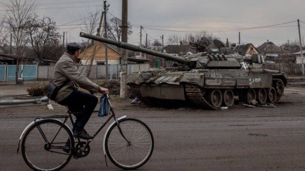 A man rides past a destroyed Russian tank in Trostyanets, north-east Ukraine.