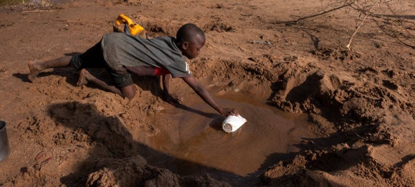 A young boy collects what little water he can from a dried-up river due to severe drought in Somalia.
