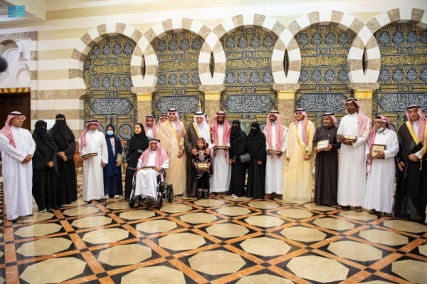 Prince Khaled Al-Faisal with the beneficiaries after distributing title documents of housing units.