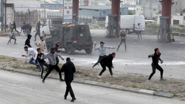 Palestinians throw stones at an Israeli military vehicle in Nablus.