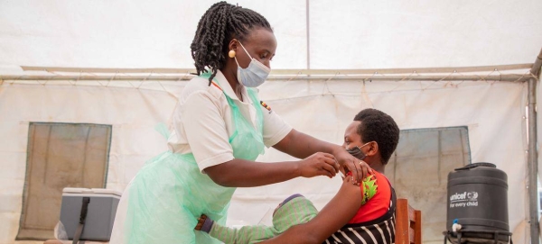 A nurse administers the COVID vaccine to a woman in a health center in Uganda.
