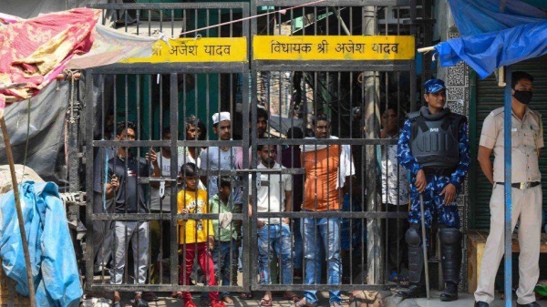 Local residents look on as a team of Rapid Action Force (RAF) patrols the area where communal violence broke during a Shobha Yatra on Hanuman Jayanti, at Jahangirpuri, on April 17, 2022, in New Delhi, India.