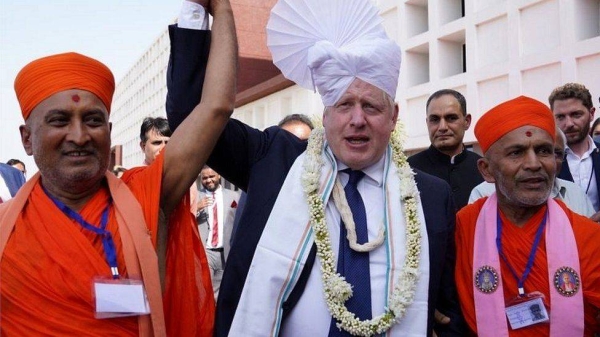 Boris Johnson walks with Hindu holymen as he visits Ahmedabad, part of his two-day trip to India, on Thursday.