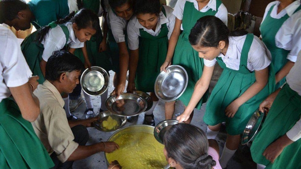 Schoolgirls receive a free mid-day meal at a government school in Nagaon, Assam.