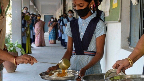 Schoolgirls receive a free mid-day meal at a government school in Nagaon, Assam.
