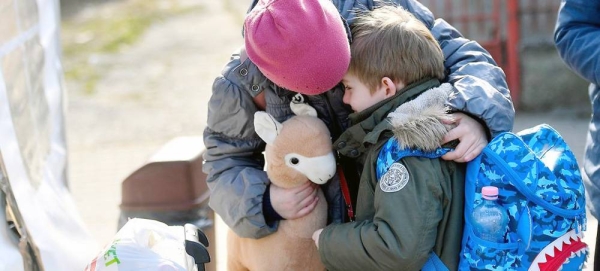 A Ukrainian girl comforts her six-year-old brother as they prepare to leave a UNICEF-supported centre in Romania for their next destination. — courtesy UNICEF/Alex Nicodim
