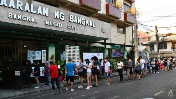 Filipinos queue on the street to vote, outside a polling station