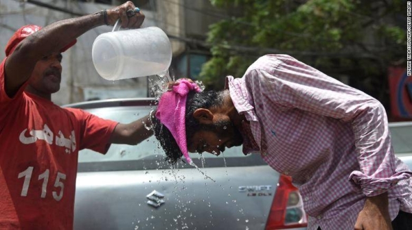 An Edhi volunteer pours water on a pedestrian along a street during a hot summer day in Karachi on May 16.