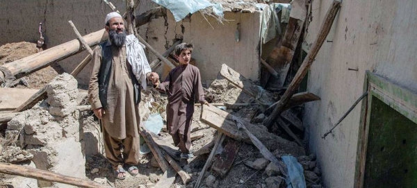 A father and son walk amidst the wreckage of their home, destroyed during the earthquake whick struck Paktika Province, Afghanistan. — courtesy UNICEF/Sayed Bidel