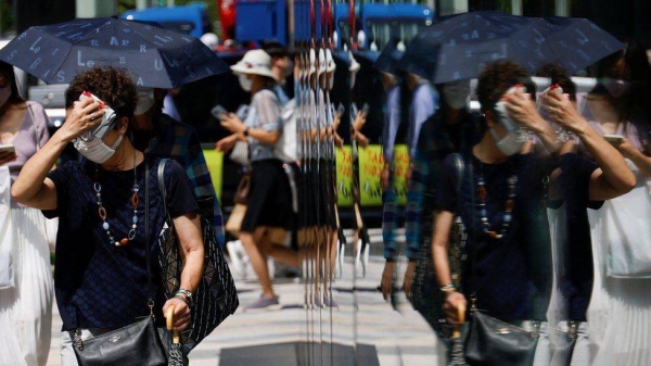 A woman wipes her face as she walks down a street in Tokyo.