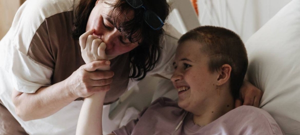 Lyudmila kisses her 13-year-old daughter Sofia's hand who is recovering after surviving a shell attack, at the specialized children's hospital ‘Okhmatdyt’ in Kyiv..jjpg