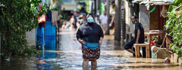 A woman walks through water in an area affected by flooding in East Jakarta, Indonesia. — courtesy UNICEF/Arimacs Wilander