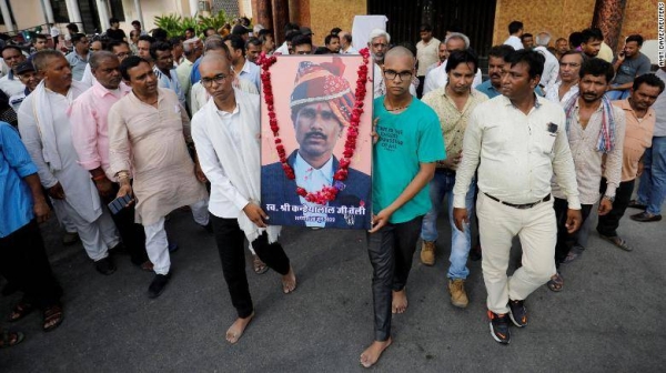 Two sons of Kanhaiya Lal Teli, the murdered Hindu tailor, carry a portrait of their father in Udaipur, Rajasthan, India, on June 30.