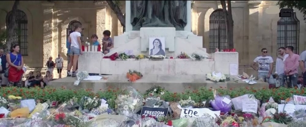 Bouquets are placed in front of a picture of Daphne Caruana Galizia in Valletta.