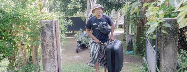 Dekha Dewandana carries his guest suitcase at Esa di Kubu Homestay in Sudaji Village, Buleleng, Bali, Indonesia. — courtesy Putu Sayoga for ILO