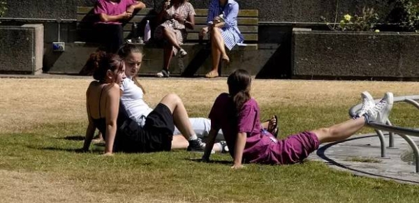 Hospital staff in London enjoy their lunch break on a small green grass patch on Thursday.