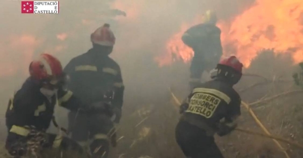 Spanish firefighters are forced to flee the flames while battling a wildfire.