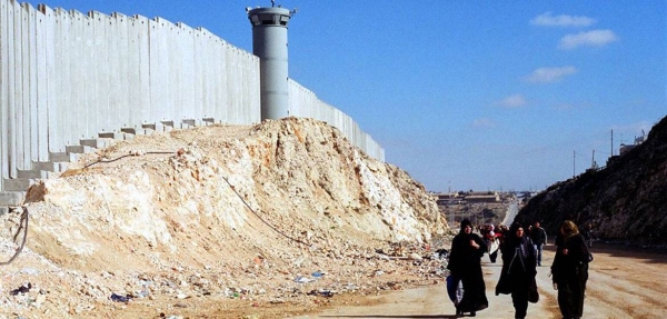 Palestinian women walk by Israel's barrier near Ramallah in the West Bank.