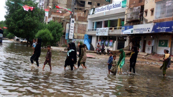 People crossing a flooded street after days of rain in Karachi. — Courtesy photo