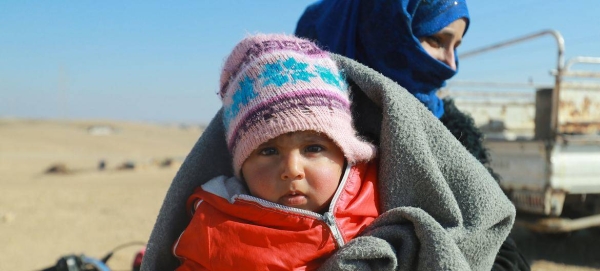 A mother and child wait for their winter aid kit at an informal settlement in Eastern rural Raqqa, Syria. (file),jpg