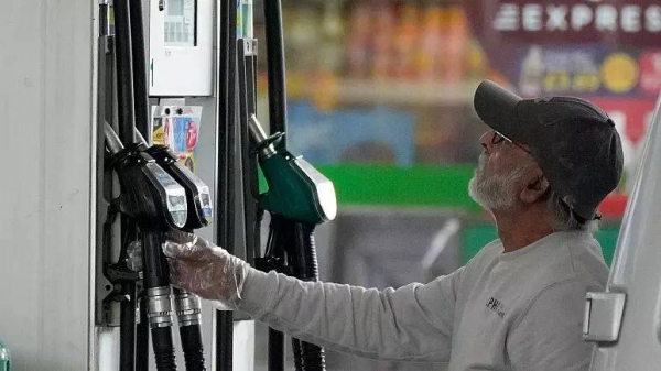 A driver looks at the petrol pump at a petrol station in London, Thursday, June 9, 2022.