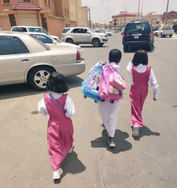 Mishal Al-Shahrani is seen carrying the bags of his sisters Sarah and Noura along with his own while returning home after school.