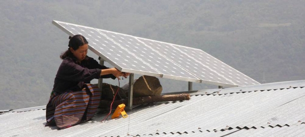 A woman installs a solar panel on a roof in Bhutan. —courtesy ADB