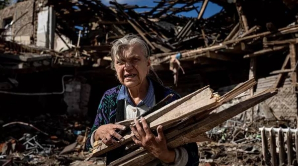 A woman collects wood for heating from a destroyed school where Russian forces were based in the recently retaken area of Izium, Ukraine