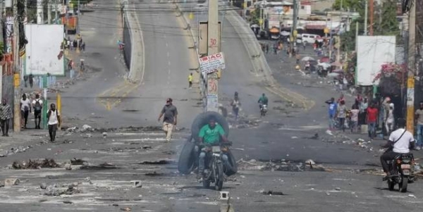 People walk on an empty street with remains of barricades during a nationwide strike against rising fuel prices, in Port-au-Prince, on Monday.