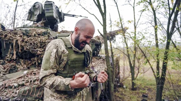 A Ukrainian soldier speaks to his brothers in arms while his unit waits for order to fire in Bakhmut, Ukraine, Sunday. — courtesy Inna Varenytsia