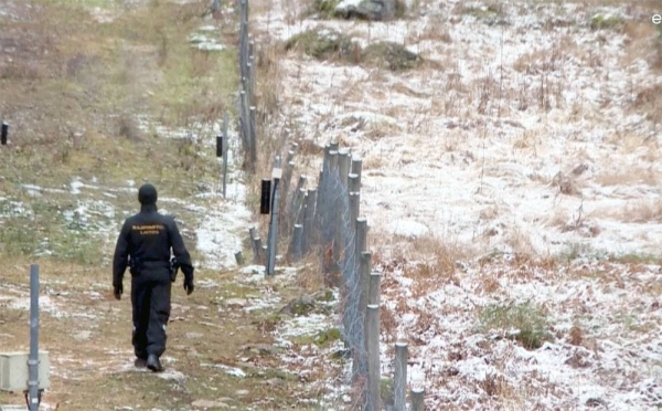 Finnish border guard patrolling fence with Russia