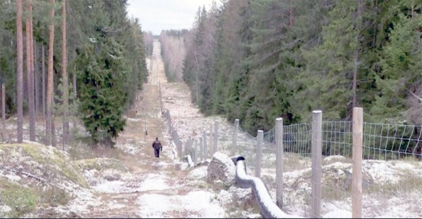 Finnish border guard patrolling fence with Russia