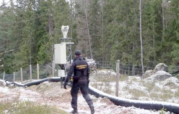 Finnish border guard patrolling fence with Russia