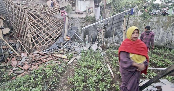 A woman walks past a house damaged by an earthquake in Cianjur, West Java, Indonesia, Monday.