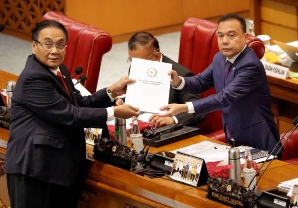 Bambang Wuryanto, head of the parliamentary commission overseeing the amendments to the criminal code, passes the newly passed law to the deputy speaker.