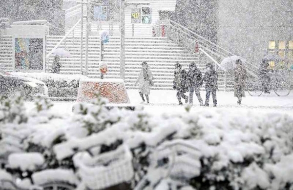 A person walks in front of Nagoya Station in Nagoya on Saturday amid the first snowfall of the season for the city. — courtesy photo Yomiuri Shimbun