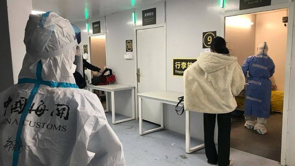 Inbound travelers line up to have samples taken for COVID tests before boarding buses to leave for quarantine hotels and facilities from Guangzhou Baiyun Airport