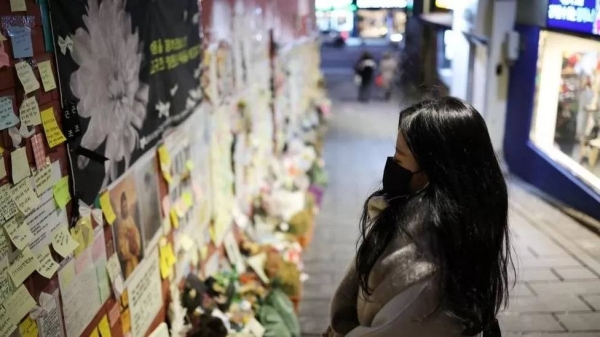 A woman reads condolence messages after last October's deadly crowd crush in Seoul.  The crush happened in a narrow sloping alley  Seoul's Itaewon district.