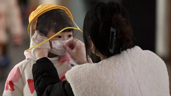 A woman arranges a face mask on a child's face at the international airport in Beijing