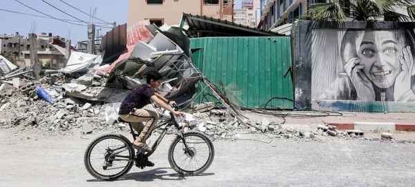 A boy rides his bike next to buildings destroyed after Israeli attacks in the Gaza Strip, Palestine (file). — courtesy UNRWA/Samar Abu Elouf