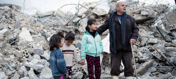 A family from the Rumaila area in Jableh district, in northwestern Syria stands close to their destroyed house. — courtesy UNICEF/Hasan Belal