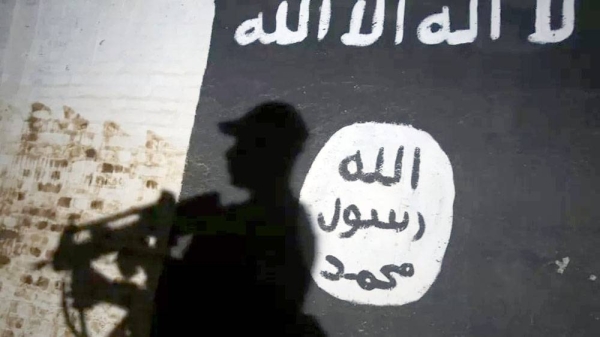 A soldier walks past a mural bearing the logo of the Daesh group ( so-called IS). — courtesy Getty Images