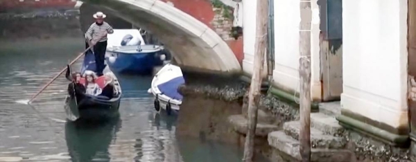 Venetian gondolas beached on the side of a canal