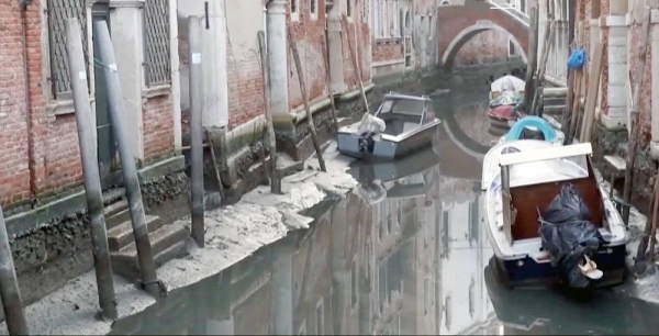Venetian gondolas beached on the side of a canal