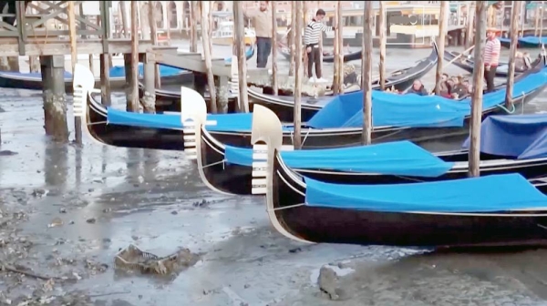 Venetian gondolas beached on the side of a canal