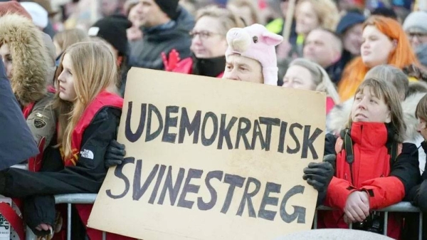 A protester holds a poster reading “undemocratic swinishness” during a demonstration against the abolishment of the public holiday. — courtesy Getty Images