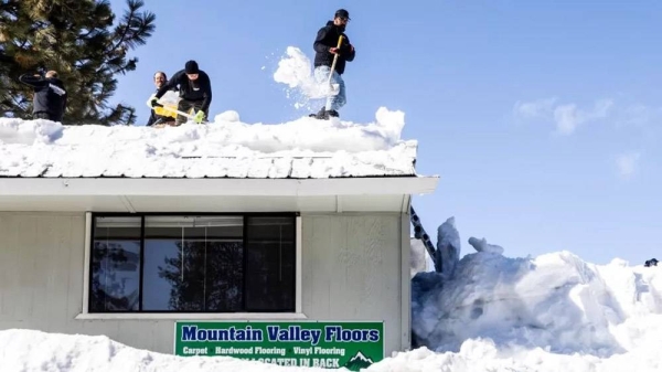 Joey Munoz shovels snow on a roof while he and his coworkers remove snow to avoid further damages to an evacuated building. — courtesy San Francisco Chronicle via Getty Images