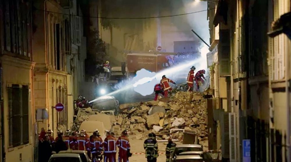 Firefighters gather near the street where a building collapsed early Sunday, in Marseille, southern France.