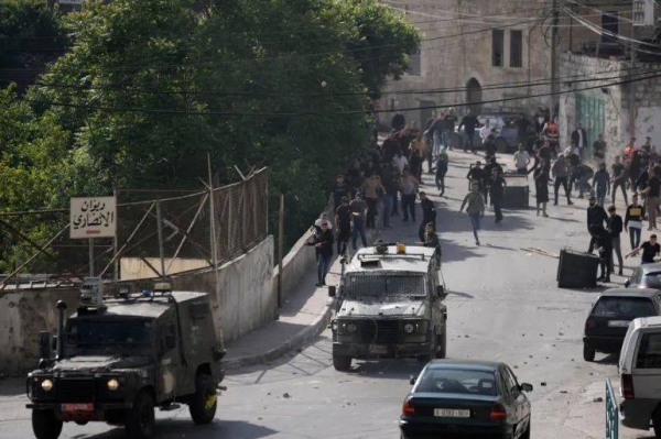 Palestinians chase Israeli military vehicles following an arrest raid in the occupied West Bank city of Nablus on May 9